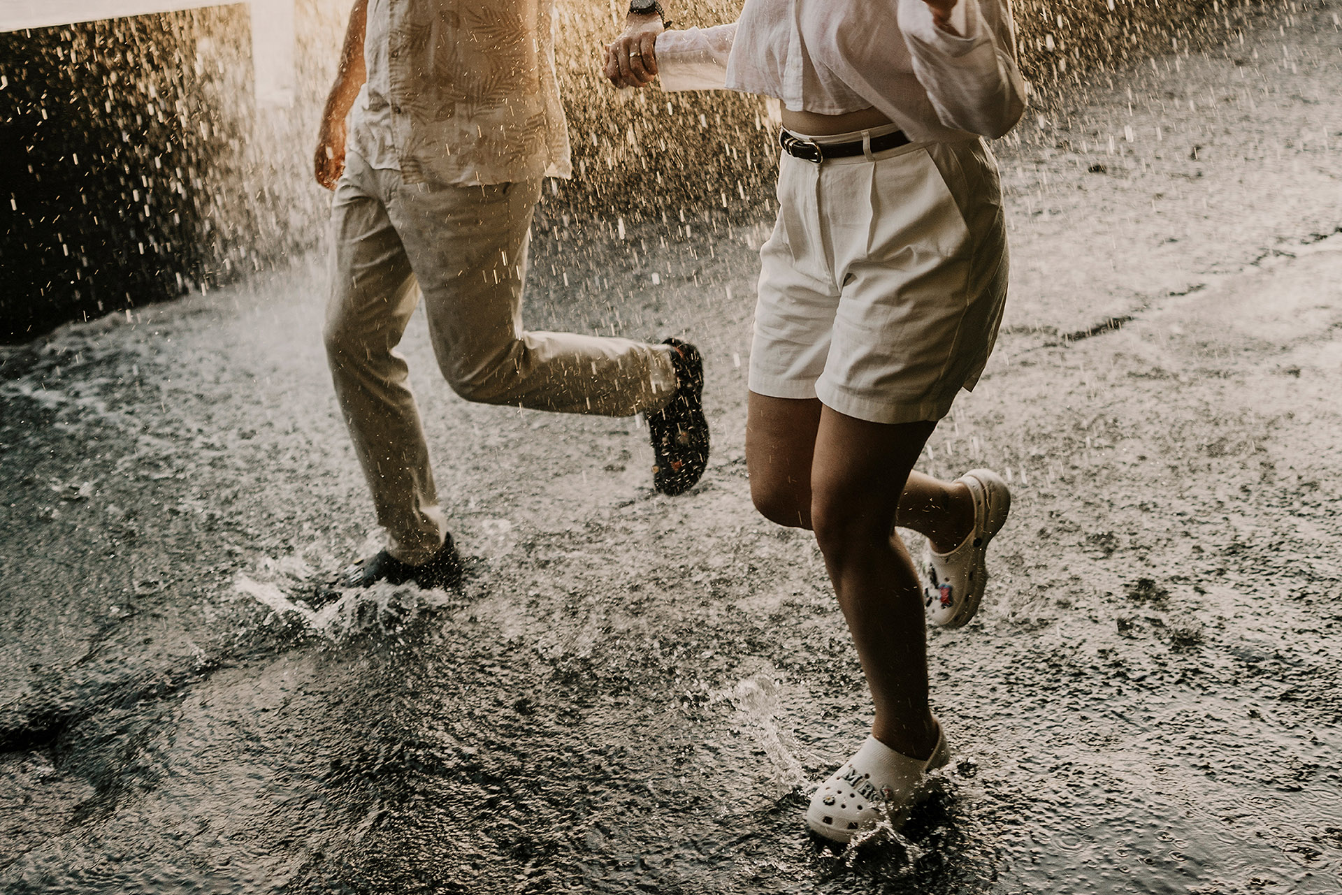 Sesja na Maderze. Para młoda biegnąca pod wodospadem podczas sesji poślubnej na Maderze, zbliżenie na nogi i chlapiącą wodę, Cascata dos Anjos by Camera Folks Wedding Photo & Video.