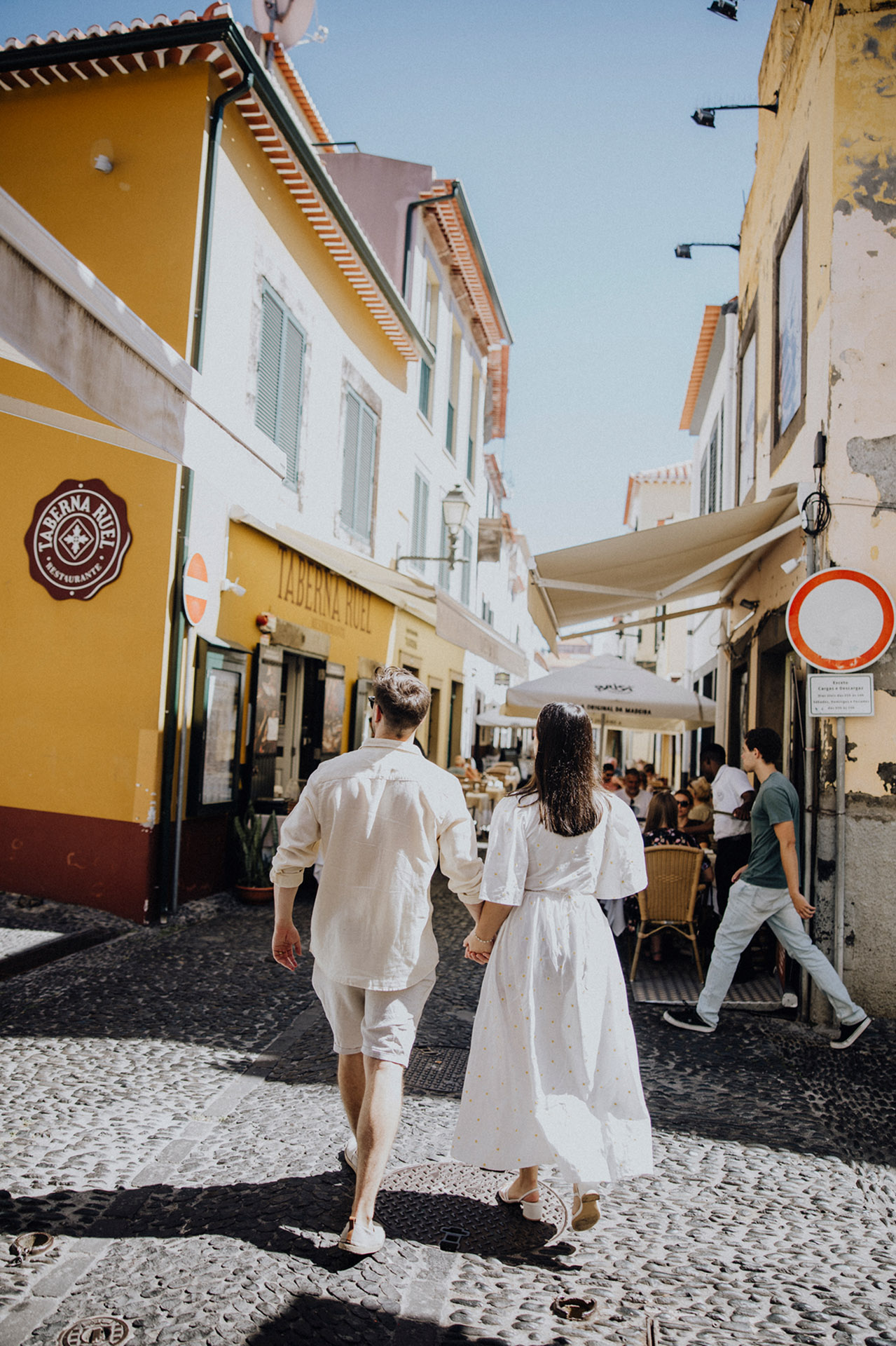 "Para młoda spacerująca po urokliwej, brukowanej uliczce Funchal na Maderze, ślubna sesja plenerowa, miejski klimat by Camera Folks Wedding Photo & Video.