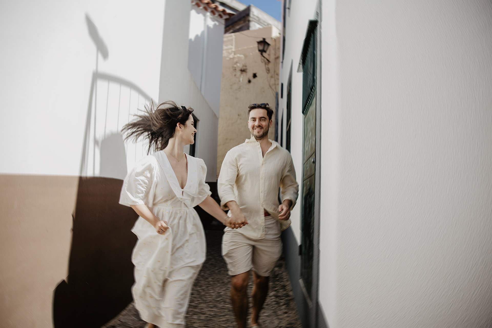 K&D radośnie biegnący po brukowanej uliczce Funchal na Maderze, trzymający się za ręce, spontaniczna sesja poślubna by Camera Folks Wedding Photo & Video.