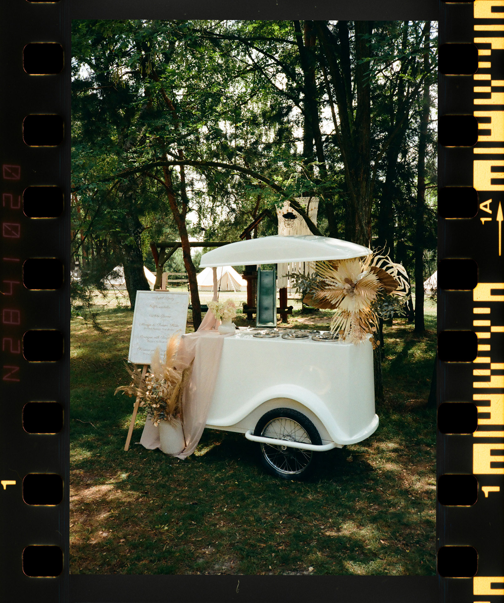 Analogowy skan mobilnej budki z lodami Dwie Kulki na tle zieleni, ujęcie z reportażu ślubnego K&D w Sielsko Anielsko, wykonane przez Camera Folks – Wedding Photo & Video.