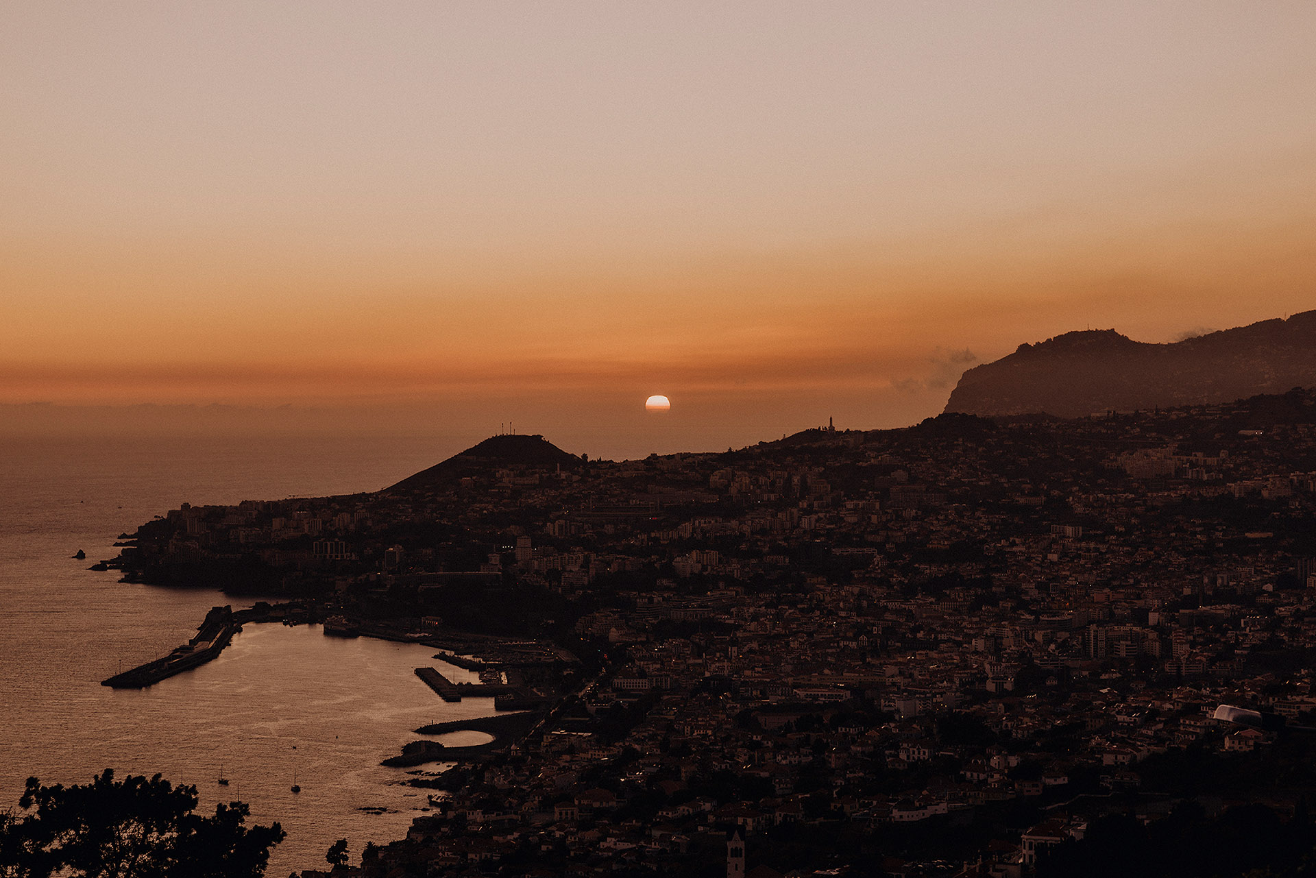 Zachód słońca nad Funchal, Madera, widziany z Miradouro das Neves, pomarańczowe niebo nad miastem i oceanem, fotografia krajobrazowa by Camera Folks Wedding Photo & Video.